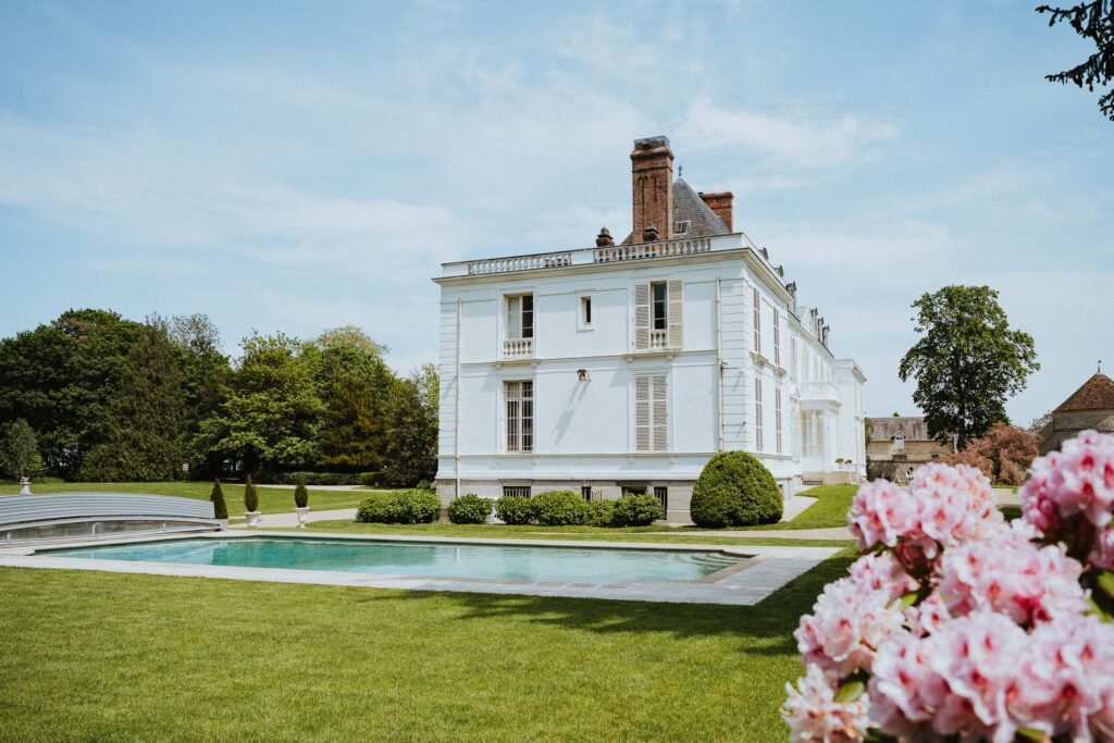 Vue latérale du Château Barthélemy avec sa piscine entourée d’un vaste jardin verdoyant, un lieu de mariage en Île-de-France