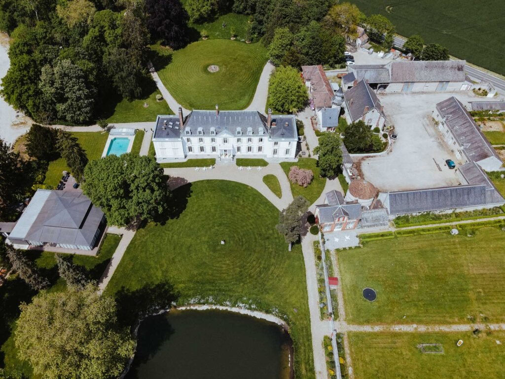 Vue aérienne du Château Barthélemy montrant ses jardins, la piscine et les bâtiments annexes, un lieu de mariage exceptionnel en Île-de-France