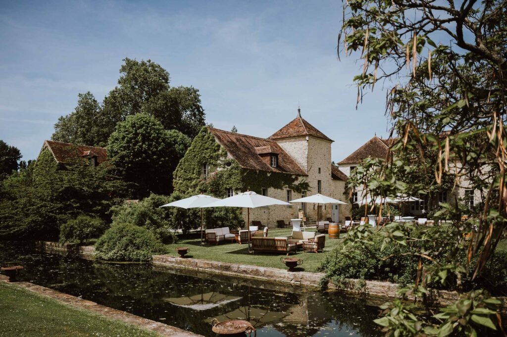 Jardin du Château de Berville avec son canal, ses parasols élégants et son cadre champêtre, idéal pour une réception de mariage en Île-de-France