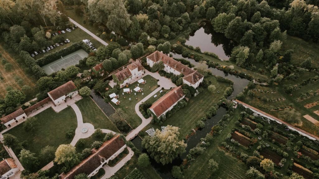 Vue aérienne du Château de Berville, dévoilant ses jardins, son canal et son cadre verdoyant pour un mariage inoubliable en Île-de-France