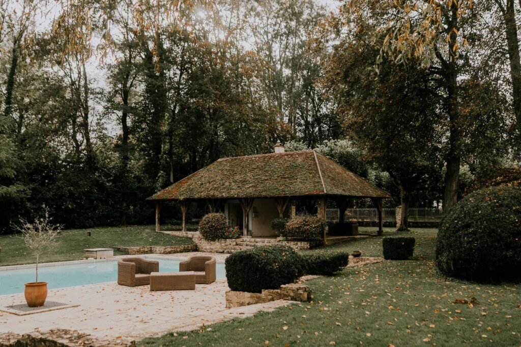 Espace détente au bord de la piscine du Moulin de Launoy, entouré d’un pavillon et de jardins arborés en Île-de-France