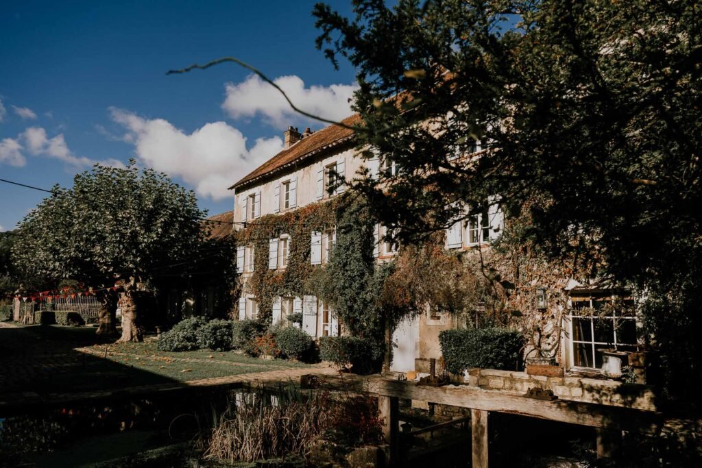 Vue extérieure du Moulin de Launoy entouré de verdure et baigné de lumière, un lieu de mariage au charme authentique en Île-de-France.