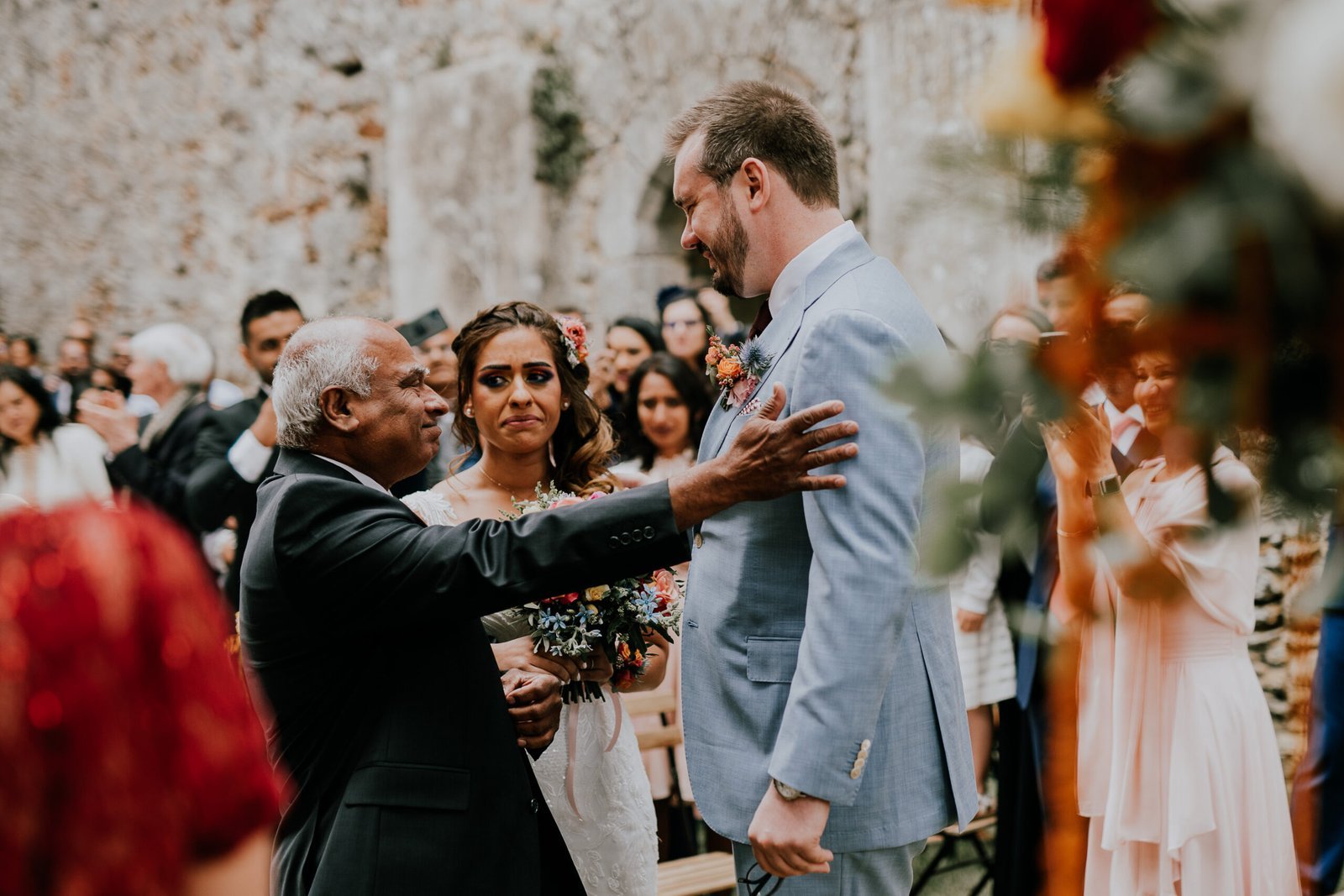 Bride and groom kissing during a sparkler exit surrounded by wedding guests in France.