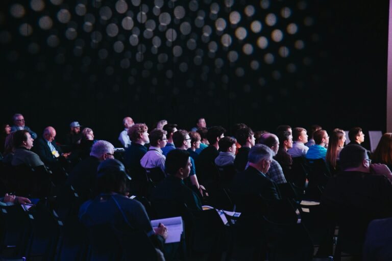 Public attentif pendant une conférence organisée dans un cadre professionnel.