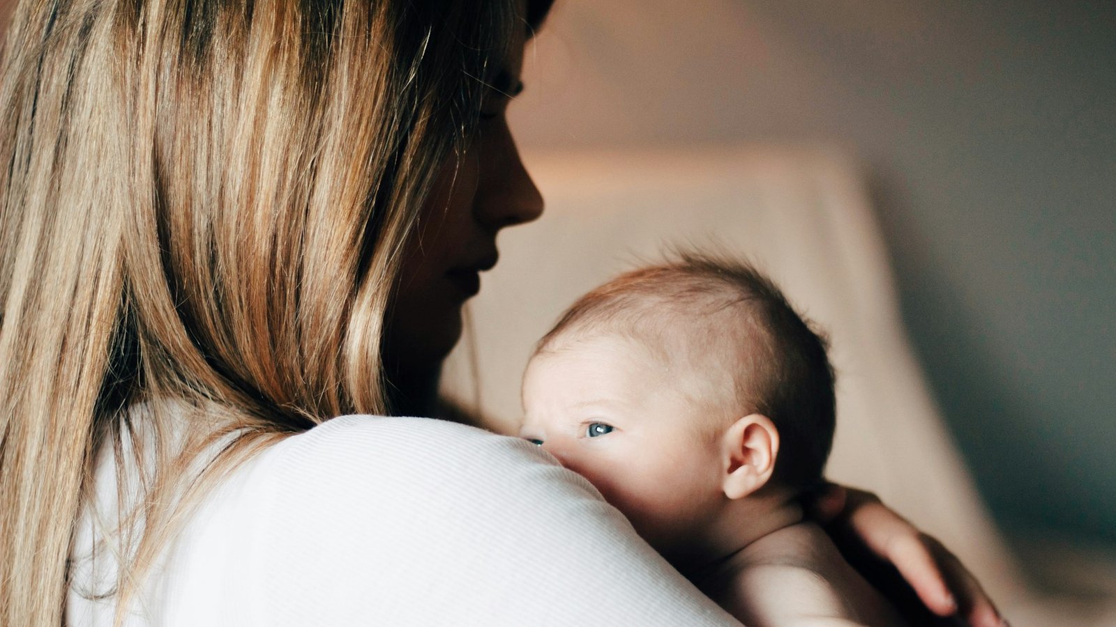 Jeune maman portant son bébé dans une lumière douce à la maison