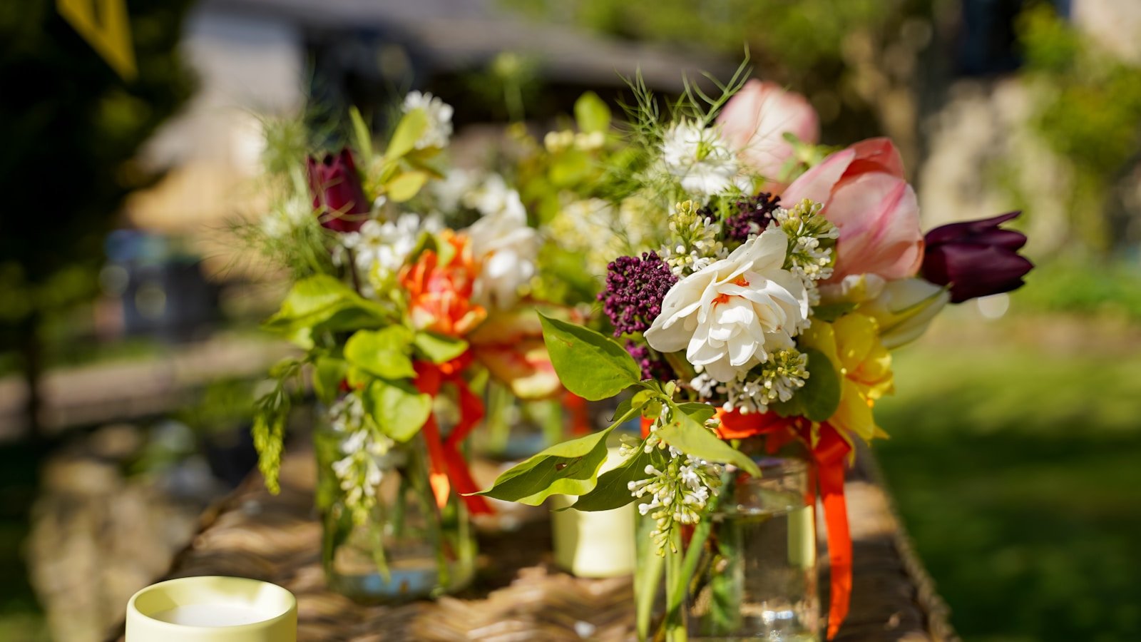 Petits bouquets de fleurs colorées dans des bocaux en verre réutilisés